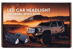 Box packaging for an LED car headlight external spotlight, featuring a desert landscape photo with a white off-road truck and the text 'LED CAR HEADLIGHT EXTERNAL SPOTLIGHT' plus feature icons. Two black spotlight units are shown in front of the box.
