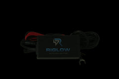 A black Biglow auto LED lighting controller box with attached black and red wires, photographed on a plain beige surface.