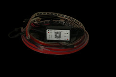 A coiled red and black LED light strip with a central black control box and a white label, photographed on a plain beige surface.