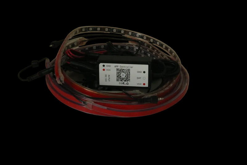 A coiled red and black LED light strip with a central black control box and a white label, photographed on a plain beige surface.
